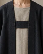 Asterhall Charcoal cloak detail showing the cloth chest bridge, discreet hooks and stitched front bands