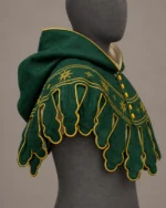 Side view of green wool medieval hood with gold sunburst embroidery, shaped dags and yellow fasteners