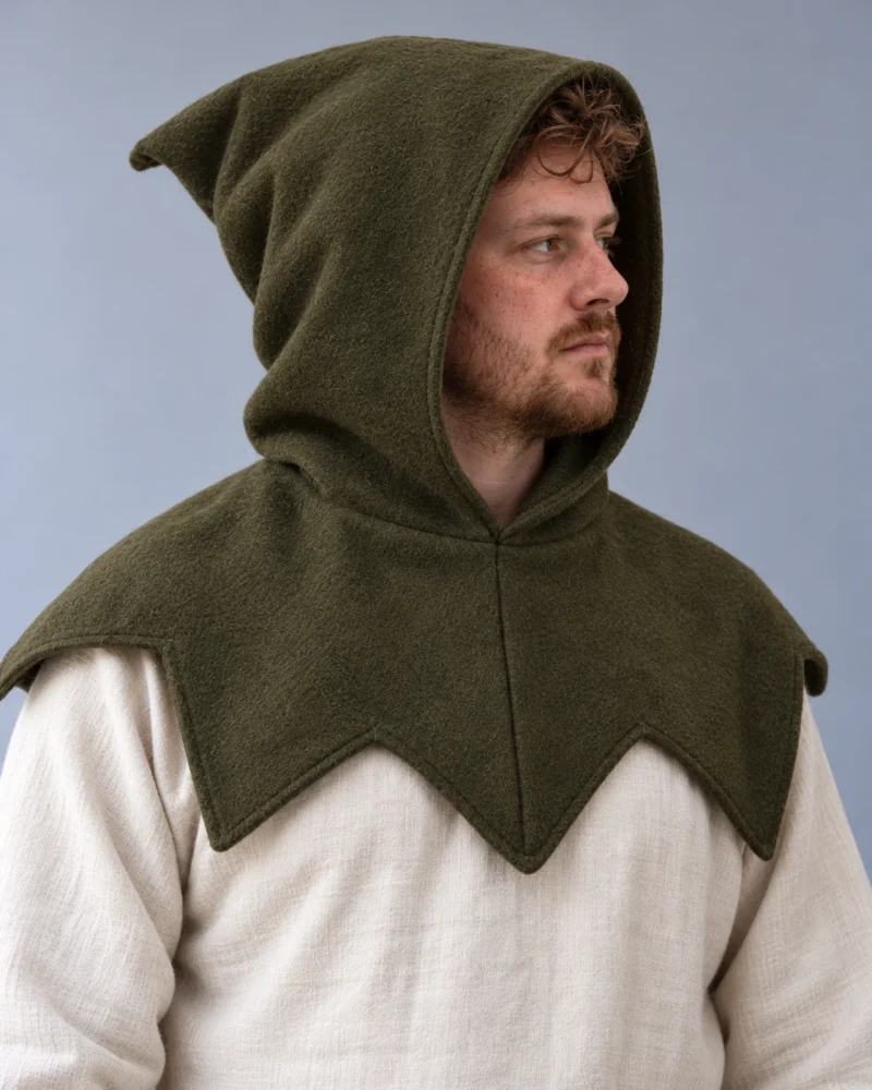 Model wearing an olive wool medieval hood with a pointed shoulder mantle over a cream linen tunic